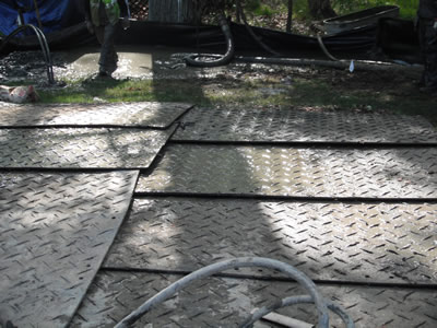 Protective steel ground mats installed to shield a residential driveway during geothermal drilling.