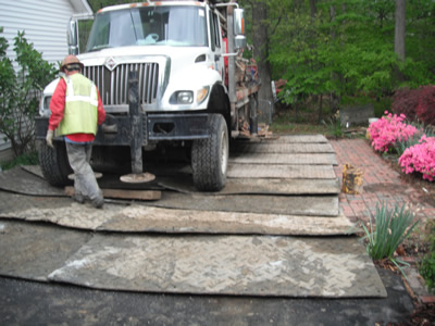 Geothermal drilling truck positioned on protective mats at a residential property.