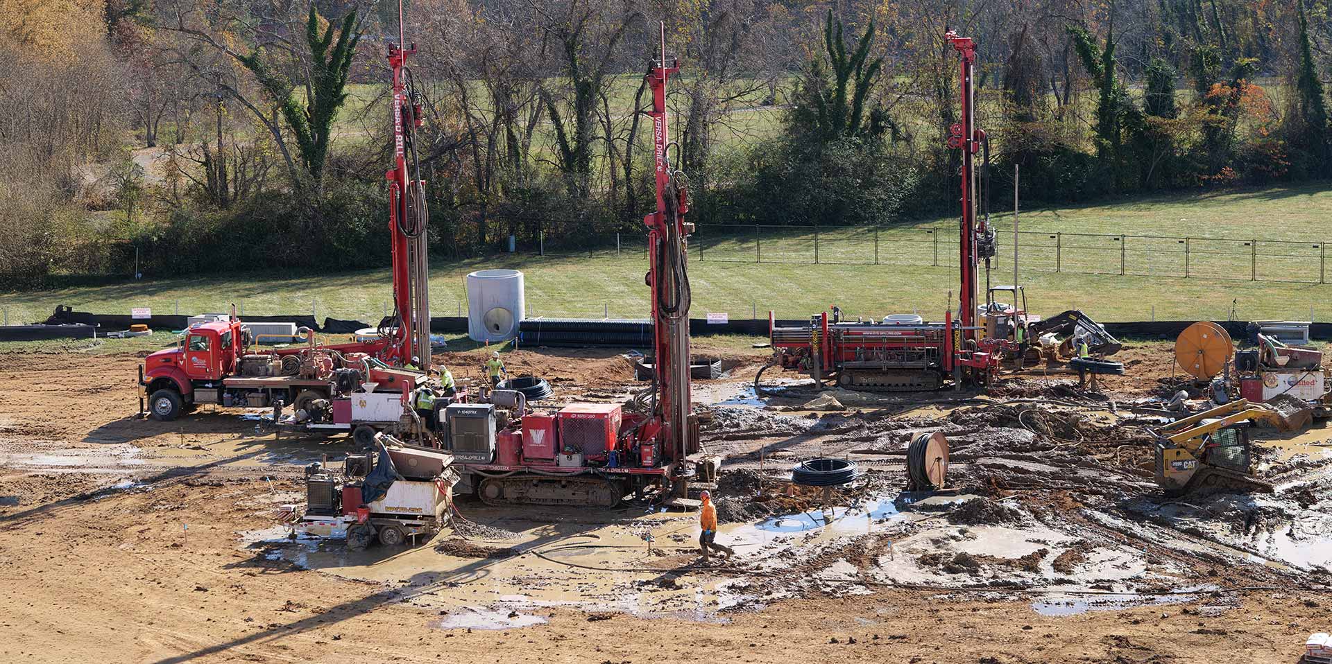 Multiple geothermal drilling rigs performing commercial ground loop installation at a large jobsite.
