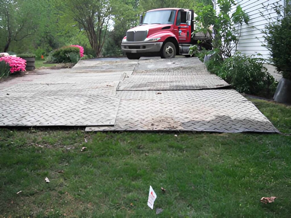 Protective ground mats installed on a residential property for geothermal drilling equipment access.