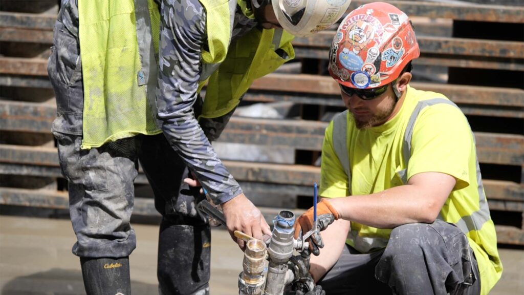 Allied Geothermal technicians assembling prefabricated geothermal piping connections on a jobsite.